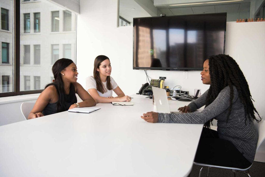 Three women in a meeting room having a lively discussion.